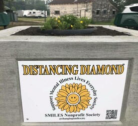 An image of the SMILES Nonprofit Society's logo, on the center piece of a Distancing Diamond.